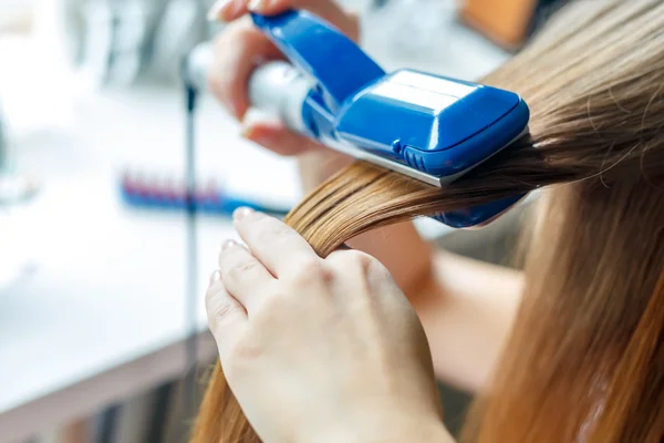 Hairdresser hairstyle models using the straightener. Closeup. Selective focus. — Stock Photo, Image