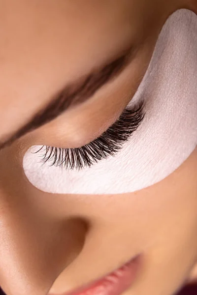 Kirpik uzatma prosedürü. Uzun kirpikli, pürüzsüz, sağlıklı ciltli güzel bir kadın gözü..