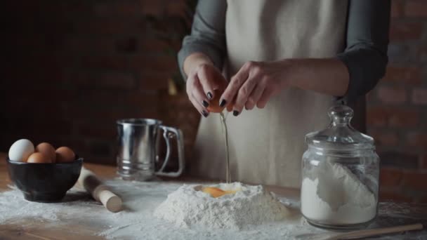 経験豊富な女性シェフは、パンを作るために小麦粉に卵をクラック.小麦粉の上に生の卵を破る手,ベーキングコンセプト.スローモーションショット. — ストック動画
