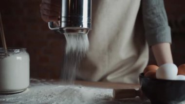 Kadın fırın şefi masayı süzgeçten un ayıklıyor, ev yapımı ekmek yapmaya hazırlanıyor. Yavaş çekim..