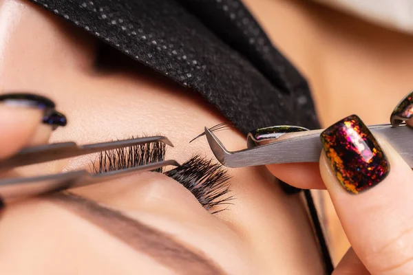 Wimpernverlängerungsverfahren. Schöne Frau mit extrem langen falschen Wimpern. Make-up, Kosmetik. Schönheit, Hautpflege. Frau in medizinischer Maske. — Stockfoto