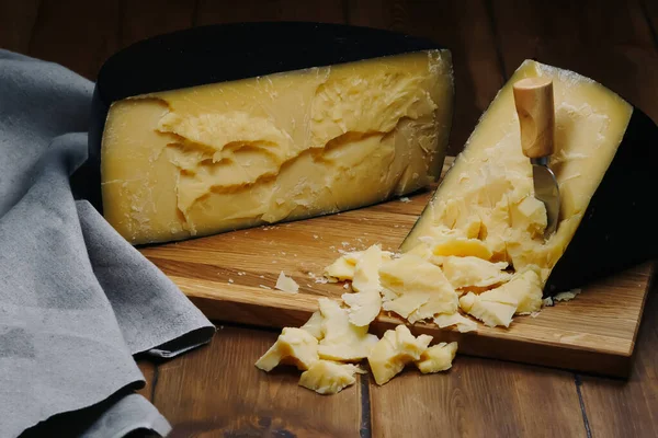 Medium hard cheese head parmesan on wooden board, with cheese parmesan knifes.