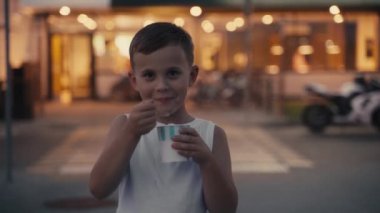 Akşam caddesinde dondurma yiyen küçük aç çocuk..
