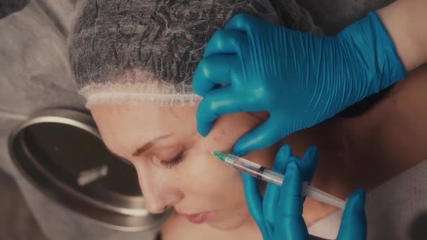 Conceito de beleza e injeções. Close-up de um esteticista que administra uma injeção na bochecha de uma mulher. — Vídeo de Stock