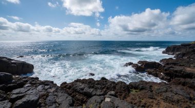 view from above of rocky coastline with waves and blue ocean