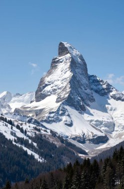 a vertical shot of the beautiful snow capped mountain peaks under a clear blue sky