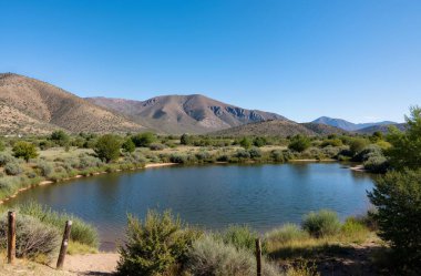 a beautiful shot of lake surrounded by mountains under a clear blue sky