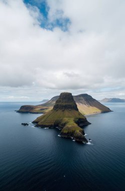 a vertical shot of a mountain in the middle of a cloudy sky during the daytime