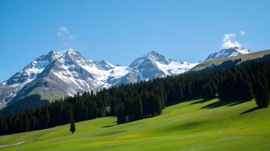 Dağları ve mavi gökyüzü olan güzel bir manzara.