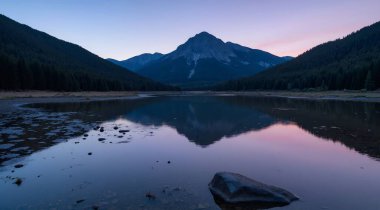 a vertical shot of a lake surrounded by rocky mountains and trees in the background during sunset