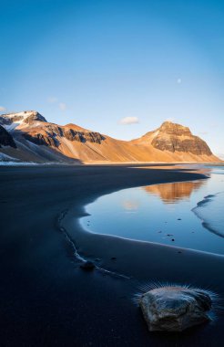 İzlanda 'da açık mavi gökyüzü olan kayalık bir sahilin güzel bir görüntüsü.