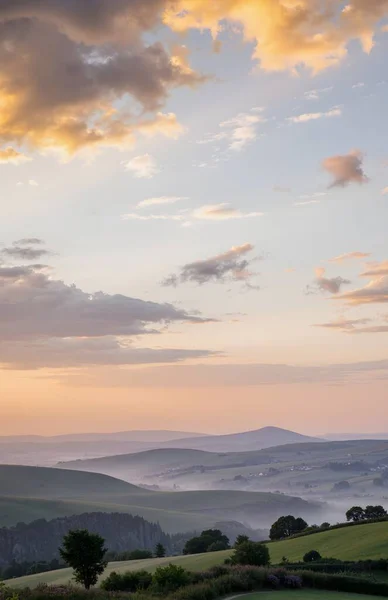 kırsal tepelerde gün doğumu tarlalar ve bulutlarla