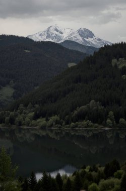 Ormandaki dağlarla çevrili güzel bir göl görüntüsü.