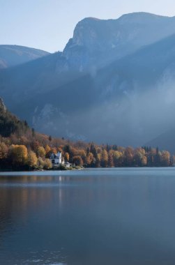 Arka planda ağaçlarla çevrili güzel bir gölün dikey çekimi.