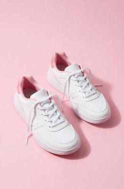 Parlak pembe arka planda spor ayakkabıları.