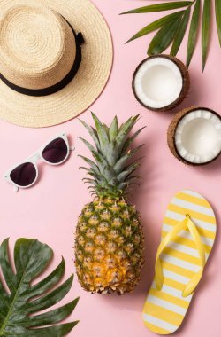 Şık güneş gözlüklü, şapkalı ve sarı arka planda ananaslı düz bir kompozisyon. Yaz mevsimi konsepti