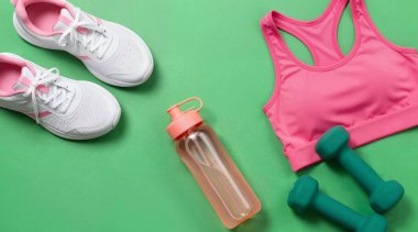 Yeşil arka planda spor ayakkabıları, şişe ve havlu.