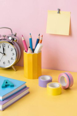 Çalar saati ve renk arkaplanı olan bir yığın kitap. okul konseptine geri dön