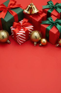 Kırmızı arkaplanda kırmızı kurdeleler ve altın toplarla dolu kırmızı noel hediye kutuları. düzlük, selamlaşma yeri, noel kartı..