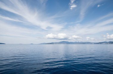 Mavi gökyüzü ve beyaz bulutlar deniz yüzeyinde