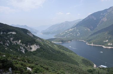 A large body of water surrounded by mountains and greenery