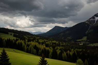 A scenic landscape of green hills and mountains under a cloudy sky