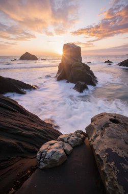 Güneşin doğuşunu deniz sahillerinde kayalar ve gökyüzüyle