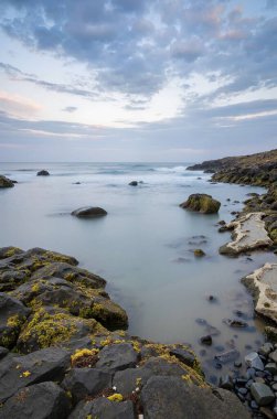 Gündüz vakti sakin bir denizde taşlı güzel bir deniz manzarasının dikey çekimi.