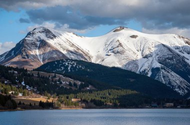 Dağlarda bir gölün güzel bir görüntüsü. Arka plandaki bulutlu mavi gökyüzünün altında.