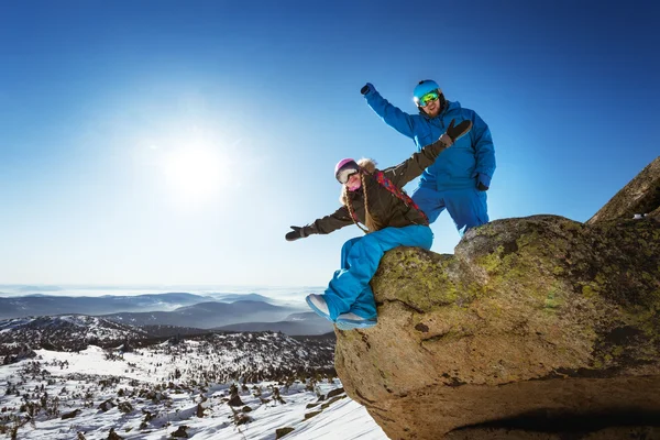 O par de snowboarders está na rocha grande — Fotografia de Stock