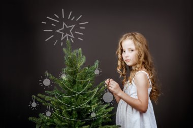kız Noel ağacının yanında duruyor