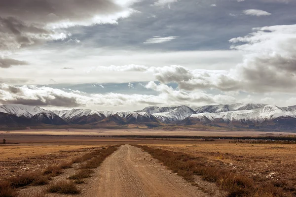 Estrada reta vai para o horizonte em montanhas — Fotografia de Stock