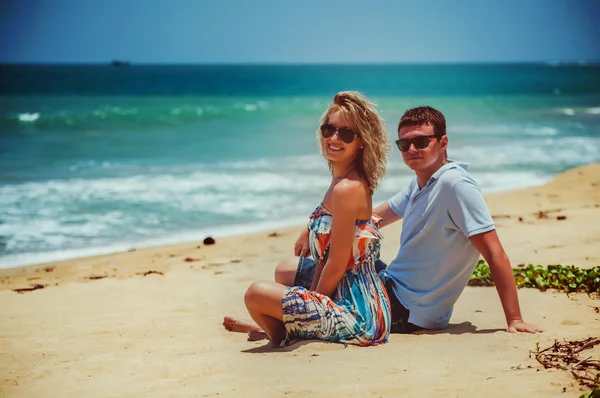 Coppia in occhiali da sole seduta su sabbia — Foto Stock