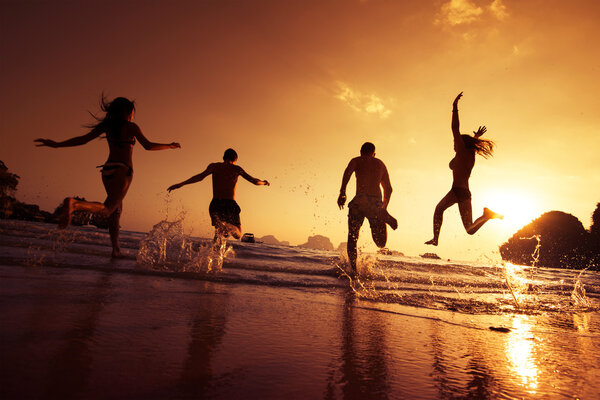 Happy friends running on a beach. Travel concept