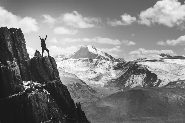 Man står i vinnare pose på klippan. Gråskala — Stockfoto
