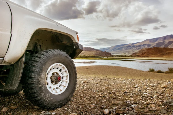 Rueda de coche SUV grande en el telón de fondo del lago — Foto de Stock