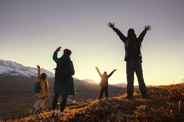 Quatro jovens caminhantes cumprimentam o pôr do sol nas montanhas — Fotografia de Stock