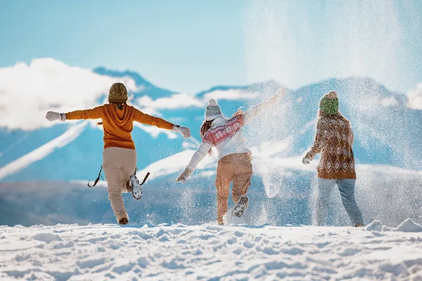 Three happy girls having fun and throwing snow in mountains — Stock Photo, Image