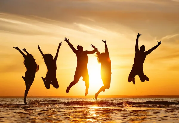 Silhouette di cinque amici che saltano in acqua — Foto Stock