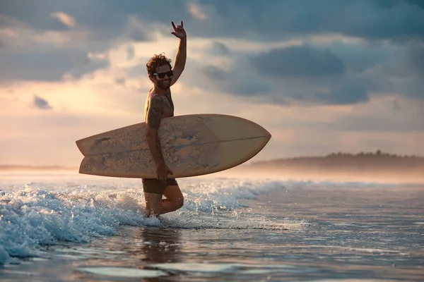 Atletisk surfare går ut från havet med surfbräda — Stockfoto
