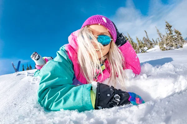 Menina feliz snowboarder encontra-se na neve e rindo — Fotografia de Stock