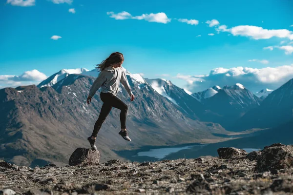 Slim chica deportiva salta de una pequeña piedra en las montañas — Foto de Stock