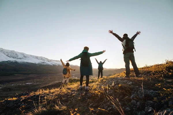 Caminhantes felizes com braços erguidos nas montanhas do pôr do sol — Fotografia de Stock