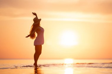 Mutlu zayıf bayan günbatımı kumsalında dans ediyor
