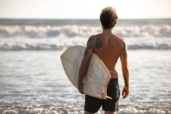 Real Bali surfař stojí se surfařem proti vlnám oceánu — Stock fotografie