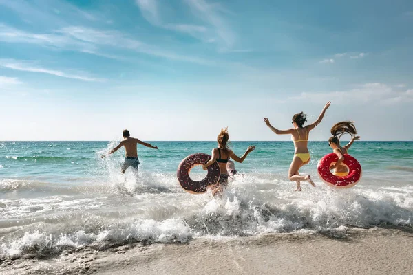 Des amis heureux s'amusent sur la plage et courent à la mer — Photo