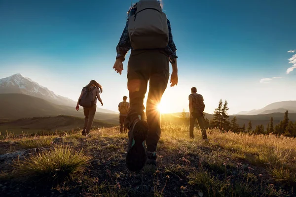 Gruppe von Sportlern wandert bei Sonnenuntergang mit Rucksäcken in den Bergen — Stockfoto