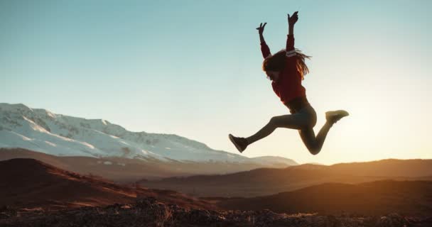 Паралакс відео зі стрибками дівчина в горах заходу сонця — стокове відео
