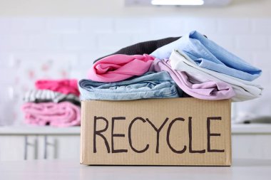 Giysilerle dolu renkli bir kutu, açıkça Geri Dönüşüm etiketi ile, sürdürülebilir ve eko-dostça moda tercihlerini destekliyor