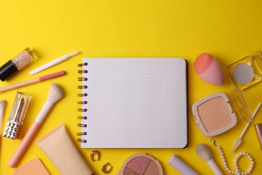 Üst Görünüm Kozmetik Düzeni Fırçalar, Paletler, Sünger, Ruj ve Yumuşak Bej Yüzey Üzerine Dizilmiş Not Defteri